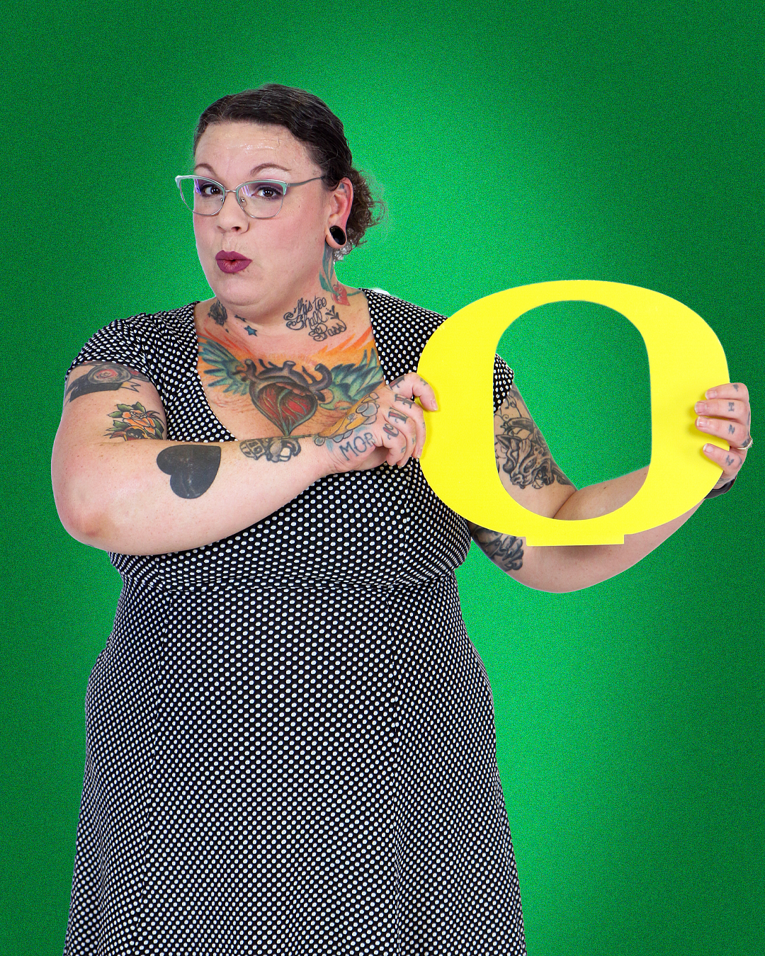 student blair hickock holding a yellow 'o" in front of a uo green solid color background