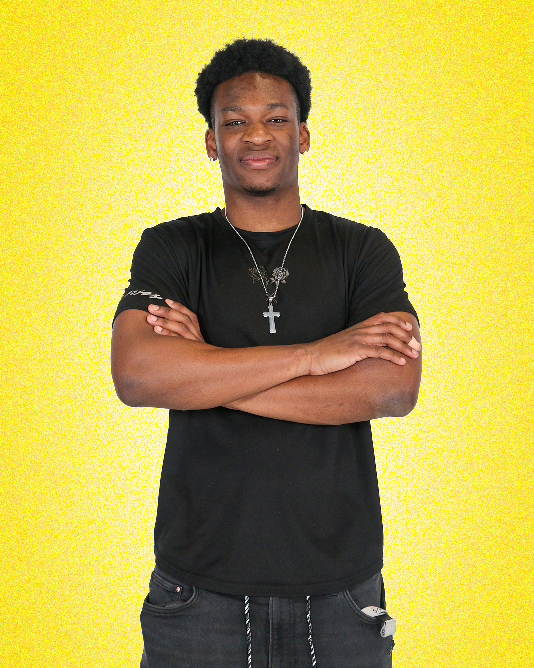 student fedi anifua proudly posing in front of a uo yellow solid color background