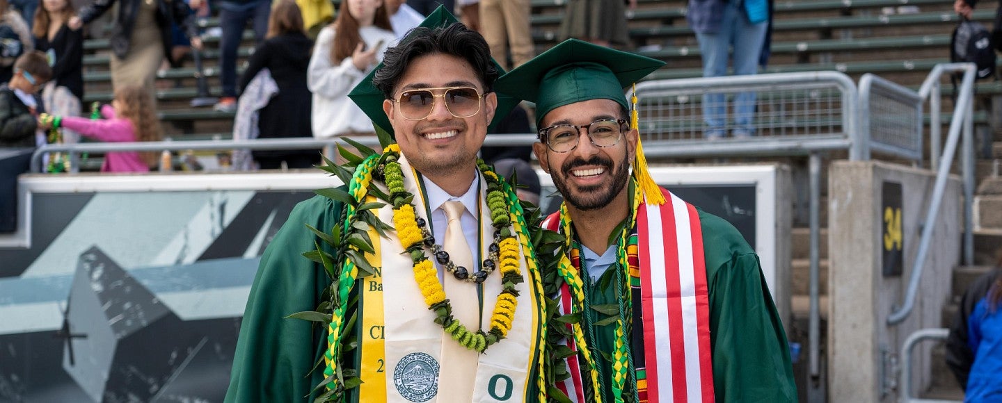 two students pose at graduation