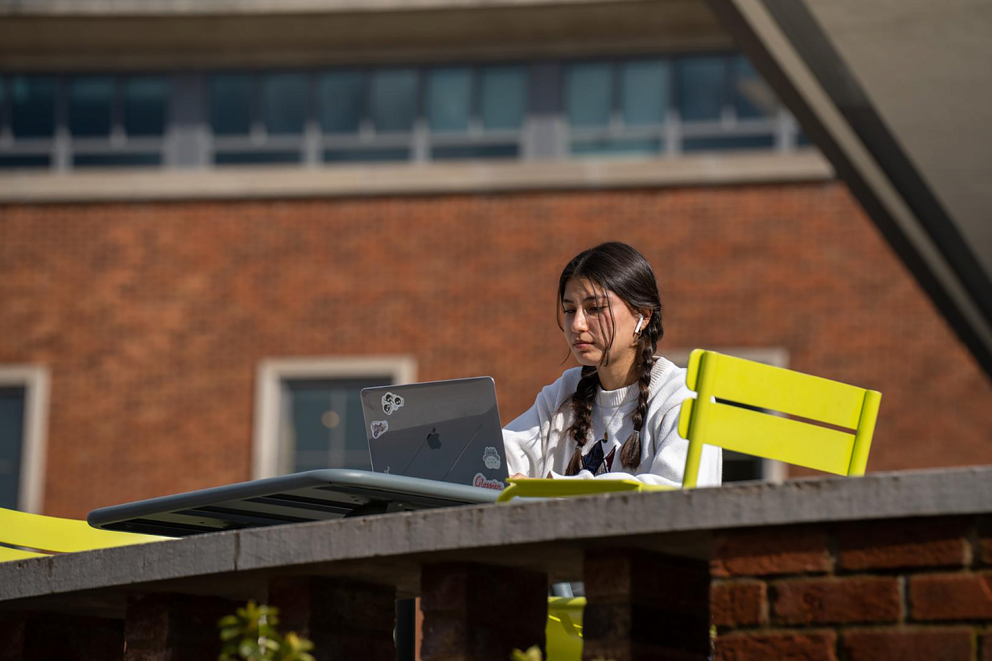 student on laptop outside in erb memorial union on a sunny day studying