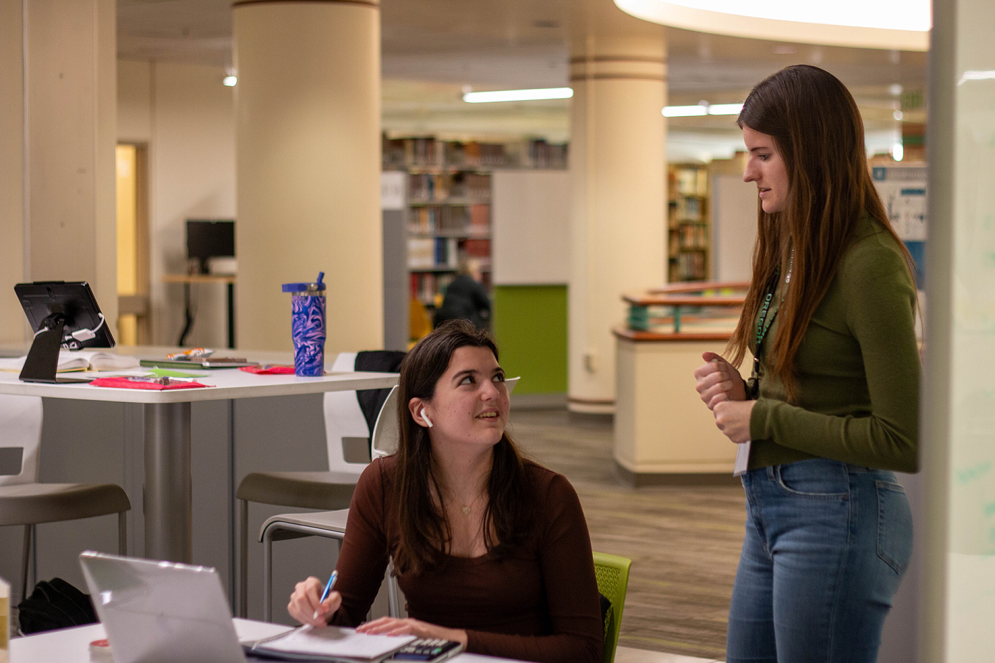 tutoring and academic engagement students talking to each other, one student is standing and the other is sitting at table