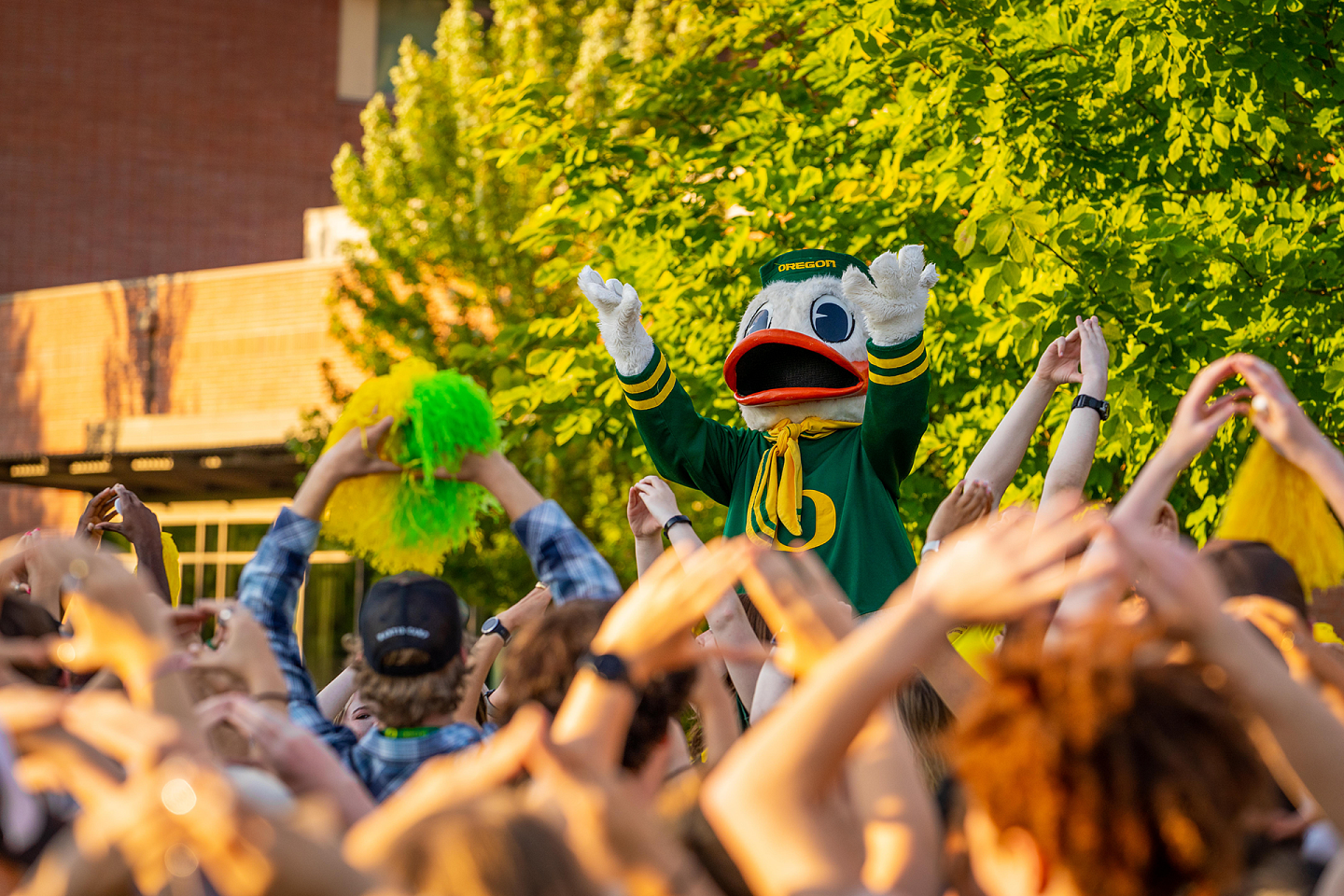 students with the duck in a crowd using their hands to form an "O" shape