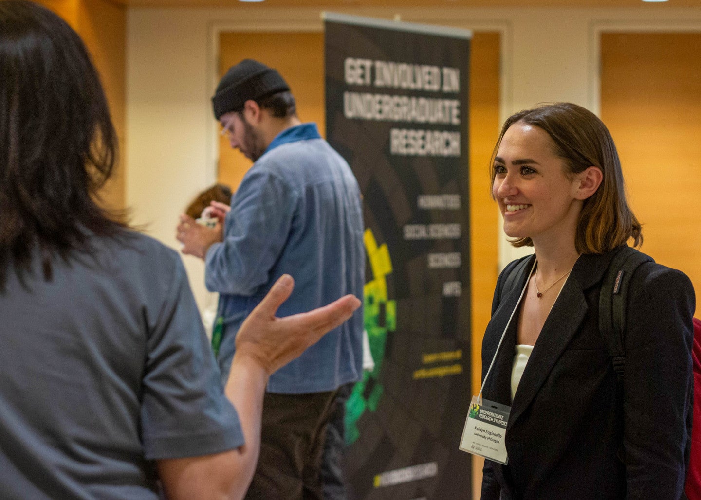 symposium participant talking to person near signage for the event