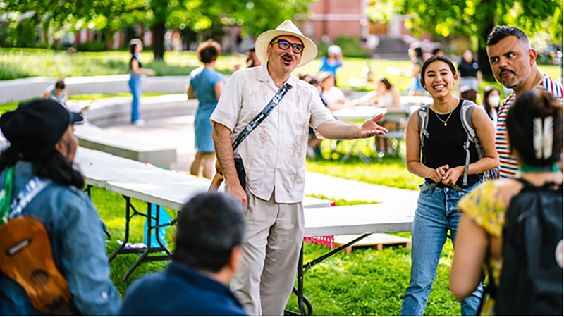 students and professors gather outside during a sunny day