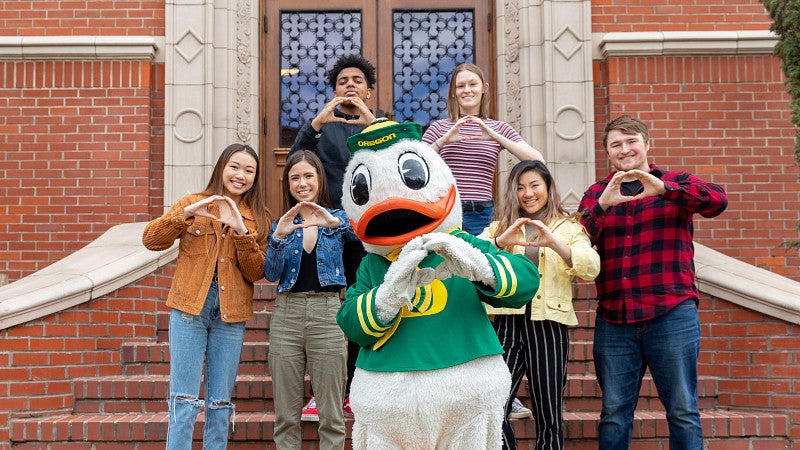 UO students throw the O with the Duck mascot.