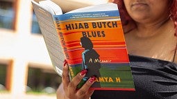 Image of person reading and holding up a copy of Hijab Butch Blues