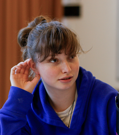 student in a purple hoodie in a workshop looking up at something