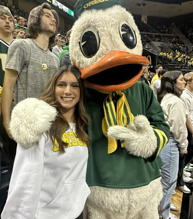 talia gutierrez posing with the duck mascot at a basketball game