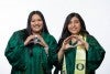 Pathway Oregon graduates Two female students smiling, wearing UO green graduation gown, and throwing their O